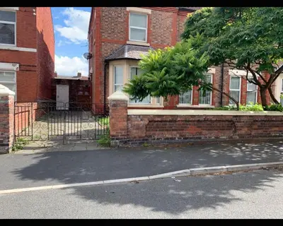 a brick house with a tree in front of it at Marley Mansions Clarendon 65 in Wallasey