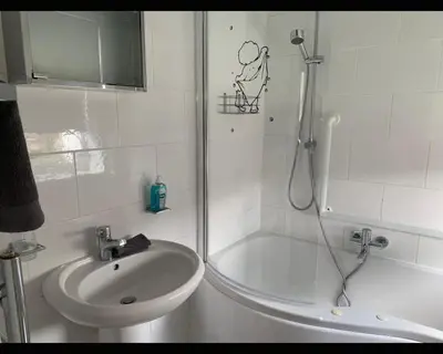 a white bathroom with a shower and a sink at Marley Mansions Clarendon 65 in Wallasey