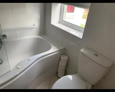a bathroom with a white tub and a toilet and a window at Marley Mansions Clarendon 65 in Wallasey