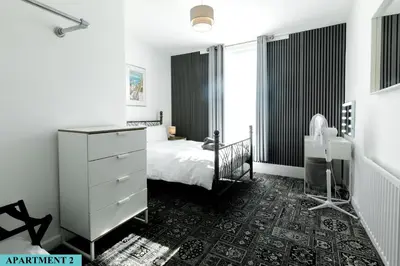 a black and white bedroom with a bed and a dresser at St Luke's 2 in Liverpool