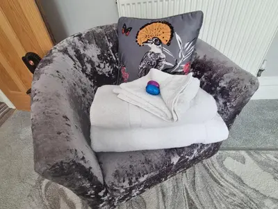 a grey chair with a pillow on it at Tiffy's Place in Blackpool