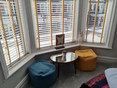 a living room with a table and two windows at Tiffy's Place in Blackpool