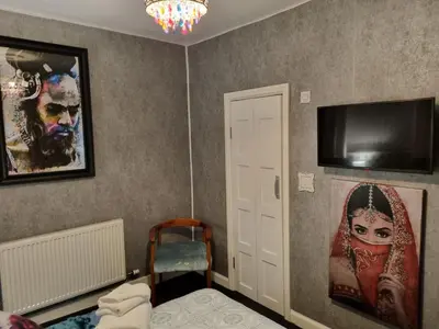 a room with a tv on the wall and a chair at Tiffy's Place in Blackpool