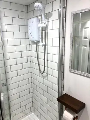 a shower in a white tiled bathroom at CLIFTON Apartments in Liverpool