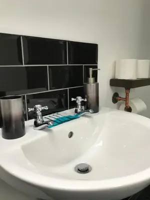 a white sink in a bathroom with black tiles at CLIFTON Apartments in Liverpool