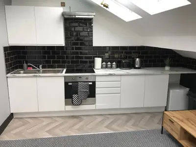 a kitchen with white cabinets and a black brick wall at CLIFTON Apartments in Liverpool