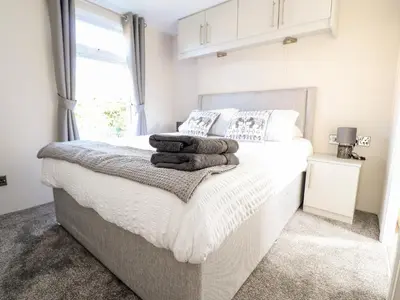 a bedroom with a white bed with towels on it at Hawthorn Lodge in Carnforth