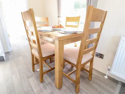 a wooden table with chairs and a plate of food on it at Hawthorn Lodge in Carnforth