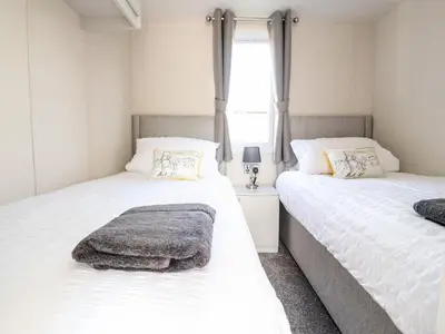 two twin beds in a bedroom with a window at Hawthorn Lodge in Carnforth