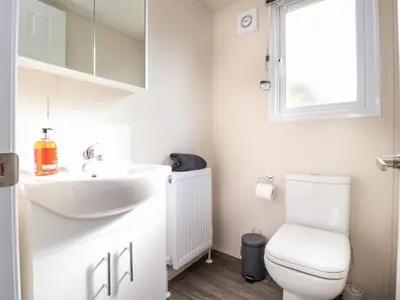 a bathroom with a sink and a toilet and a window at Hawthorn Lodge in Carnforth