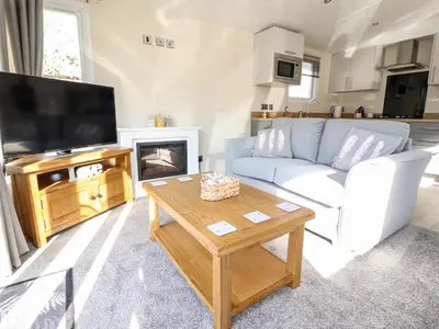 a living room with a couch and a tv and a table at Hawthorn Lodge in Carnforth