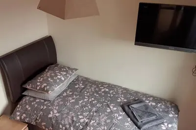 a bedroom with a bed with a tv on the wall at Combe-n-Sea in Haverigg