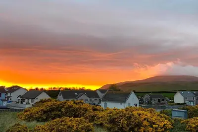 a group of houses with a sunset in the background at Combe-n-Sea in Haverigg