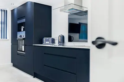 a kitchen with navy blue cabinets and a sink at Wellington Suites by Sasco Apartments in Blackpool