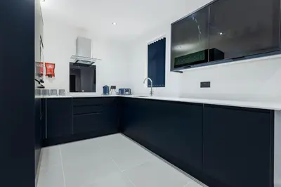 a kitchen with black cabinets and a sink at Wellington Suites by Sasco Apartments in Blackpool