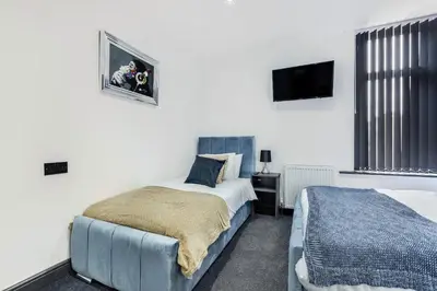 a bedroom with two beds and a tv on the wall at Wellington Suites by Sasco Apartments in Blackpool