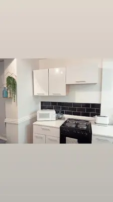 a kitchen with white cabinets and a black stove at Avril Apartments by CityNest1 in Blackpool