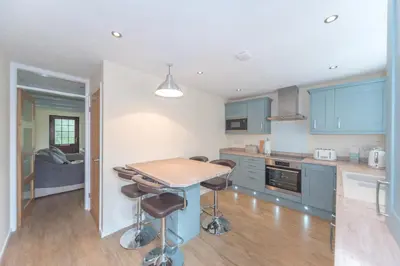 a kitchen with blue cabinets and a table and stools at Seashells Cottage in Lytham St Annes