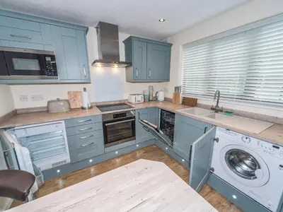 a kitchen with blue cabinets and a washing machine at Seashells Cottage in Lytham St Annes