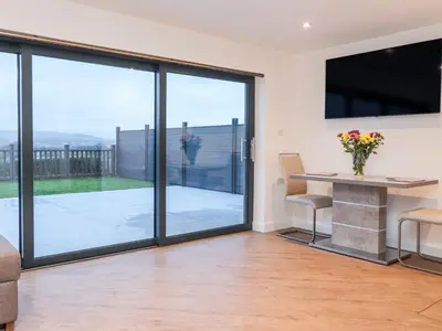 a living room with sliding glass doors and a table and chairs at ViewLangho in Blackburn