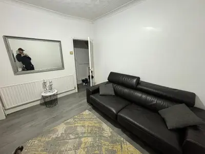a living room with a black leather couch and a mirror at Entire 3 Bedroom House- FREE PARKING in Liverpool