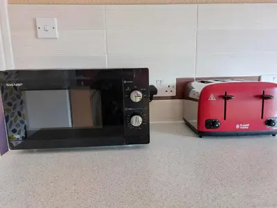 a microwave next to a toaster and a red toaster bag at Lovely 2 bedroomed flat in the centre of Longton in Longton