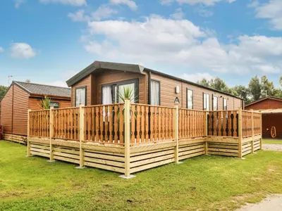 a wooden house with a wooden fence at Hedgehog Lodge in Carnforth