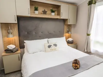 a bedroom with a bed with a dog sitting on it at Hedgehog Lodge in Carnforth