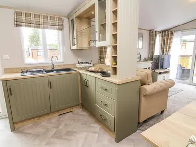 a kitchen with green cabinets and a sink at Hedgehog Lodge in Carnforth