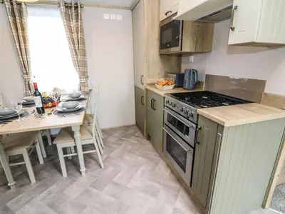 a kitchen with a table and a stove top oven at Hedgehog Lodge in Carnforth