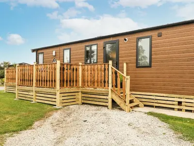 a home with a wooden deck and a house at Hedgehog Lodge in Carnforth