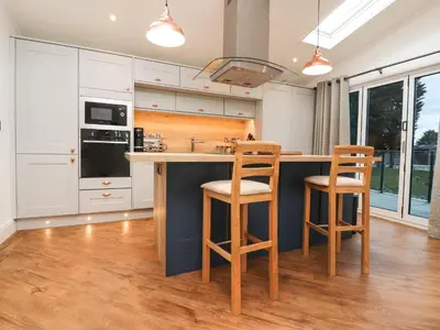 a kitchen with white cabinets and a blue island with stools at Henry Haven in Preston