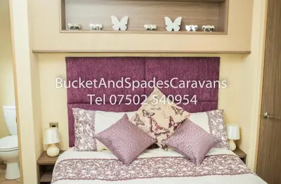 a bed with a purple headboard with butterflies above it at Blackpool caravans Marton mere in Blackpool
