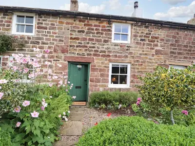 a brick house with a green door and flowers at Duckdown in Clitheroe