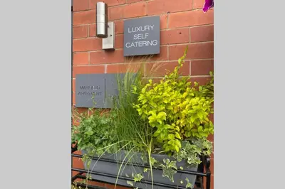 a sign on a brick wall with plants in a window at Mayfield Apartment Luxury first floor 1 bedroom apartment in Great Eccleston