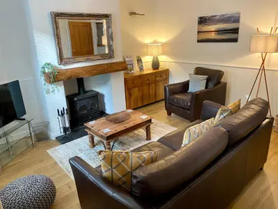 a living room with a couch and a wood stove at Riverside Cottage in Whalley