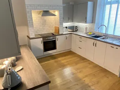 a kitchen with white cabinets and a wooden floor at Riverside Cottage in Whalley