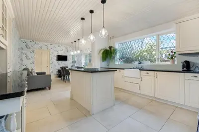 a kitchen with white cabinets and a large window at Blackpool Abode - Southlands in Blackpool