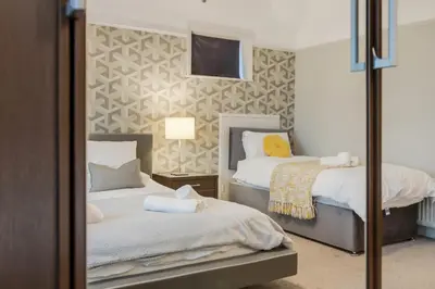 a bedroom with two beds and a mirror at Blackpool Abode - Southlands in Blackpool