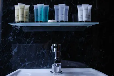 a bathroom sink with a shelf with toiletries on it at The Liverpool Inn Hotel in Liverpool