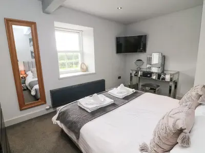 a bedroom with a large white bed with a mirror at Box Tree Farm House in Lancaster
