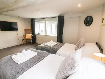 two beds in a room with a clock on the wall at Box Tree Farm House in Lancaster