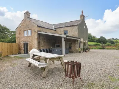 a picnic table and a chair in front of a house at Box Tree Farm House in Lancaster