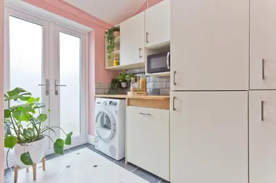 a laundry room with white cabinets and a washer and dryer at Malleus House in Barrow in Furness