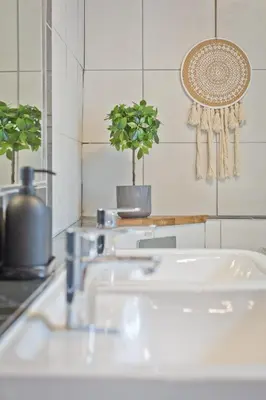 a bathroom with three sinks and two potted plants at Malleus House in Barrow in Furness