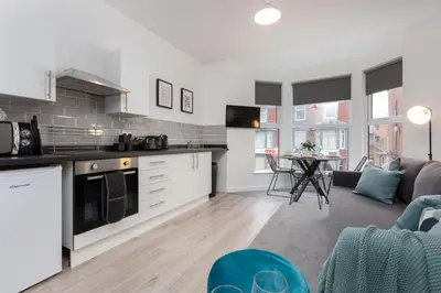 a kitchen and living room with a couch and a table at Charles Alexander Short Stay - Charnley House Apartments in Blackpool