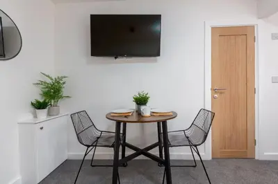 a table with chairs and a television on a wall at Charles Alexander Short Stay - Charnley House Apartments in Blackpool