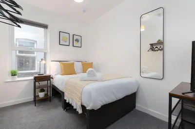 a bedroom with a bed with a mirror and a window at Charles Alexander Short Stay - Charnley House Apartments in Blackpool