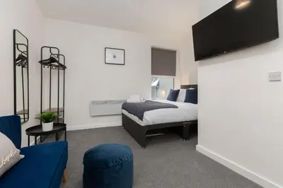 a bedroom with a bed and a tv on the wall at Charles Alexander Short Stay - Charnley House Apartments in Blackpool