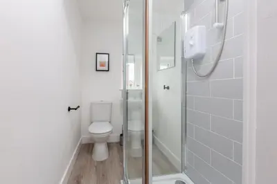 a white bathroom with a toilet and a shower at Charles Alexander Short Stay - Charnley House Apartments in Blackpool